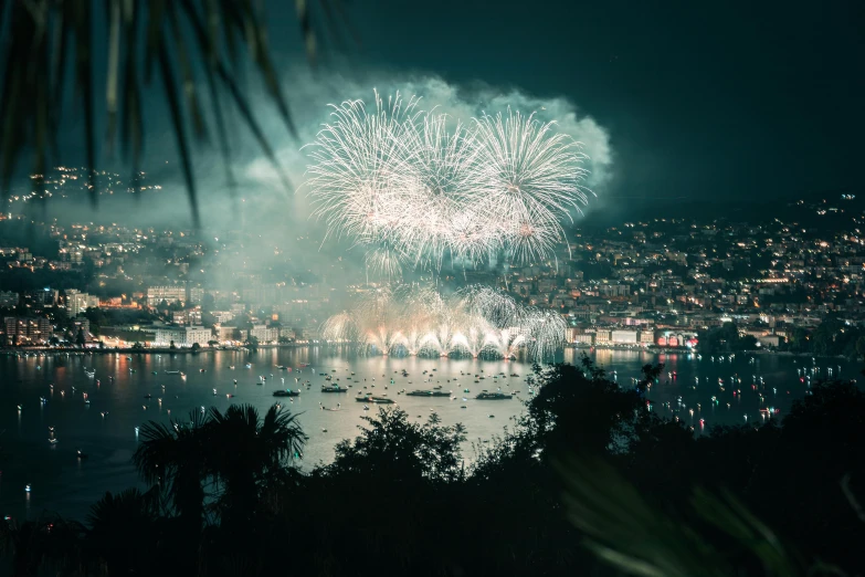 fireworks and boats glow over a city at night