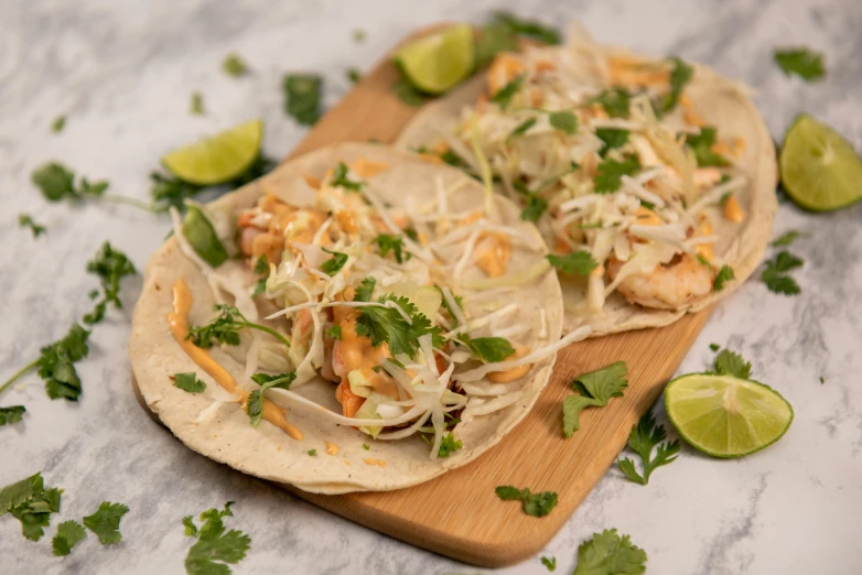 two tacos with toppings on wooden  board on granite table