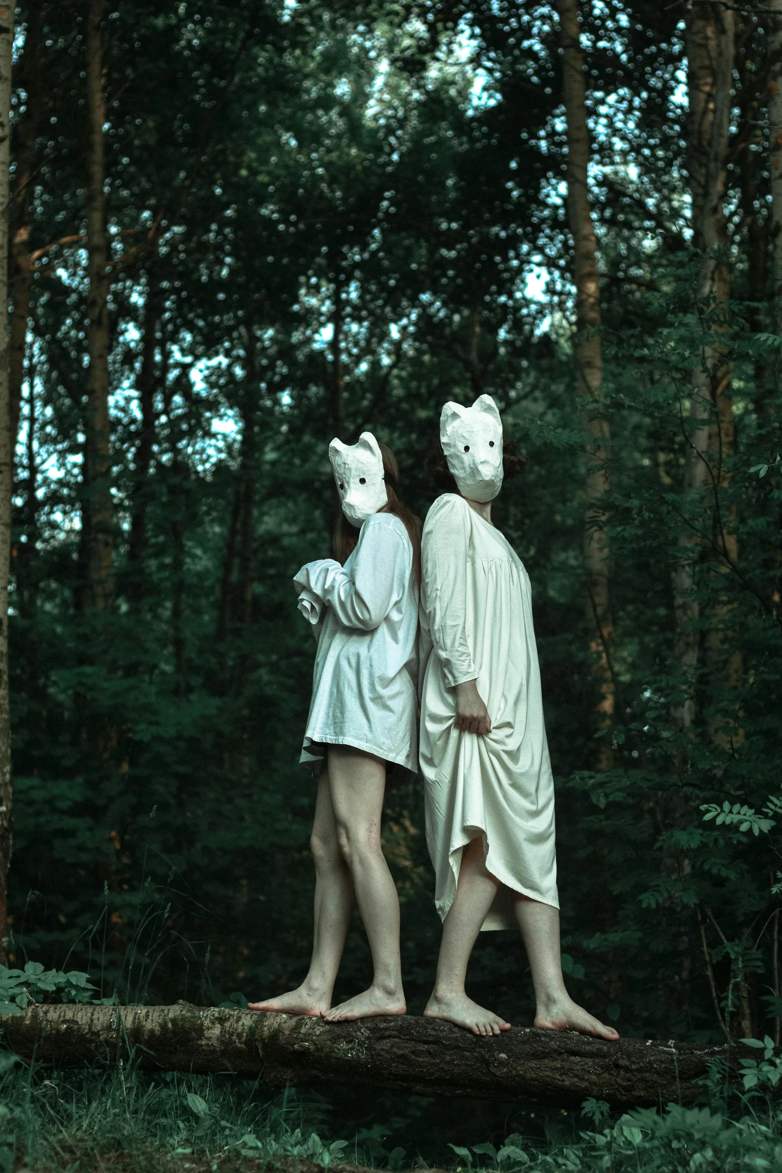 a man and woman in white are standing on a log