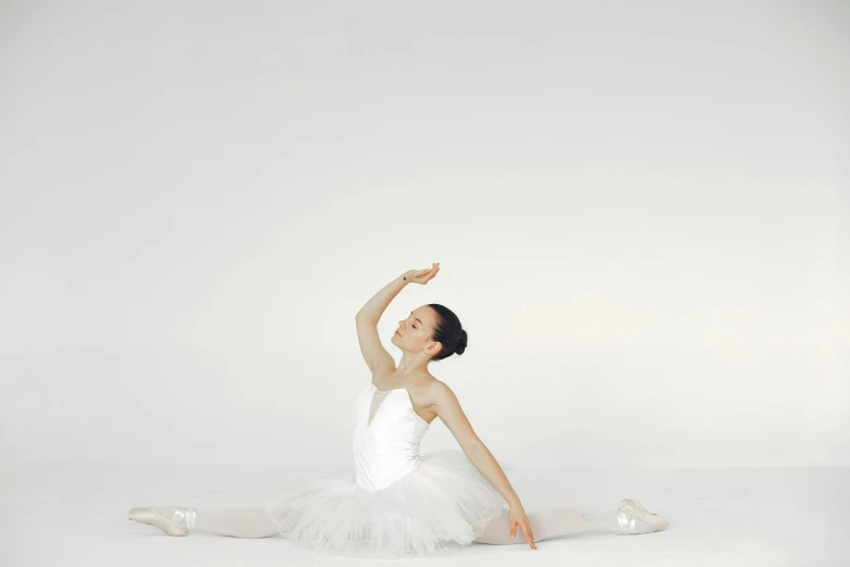 a ballerina kneeling down on the floor with her arm extended