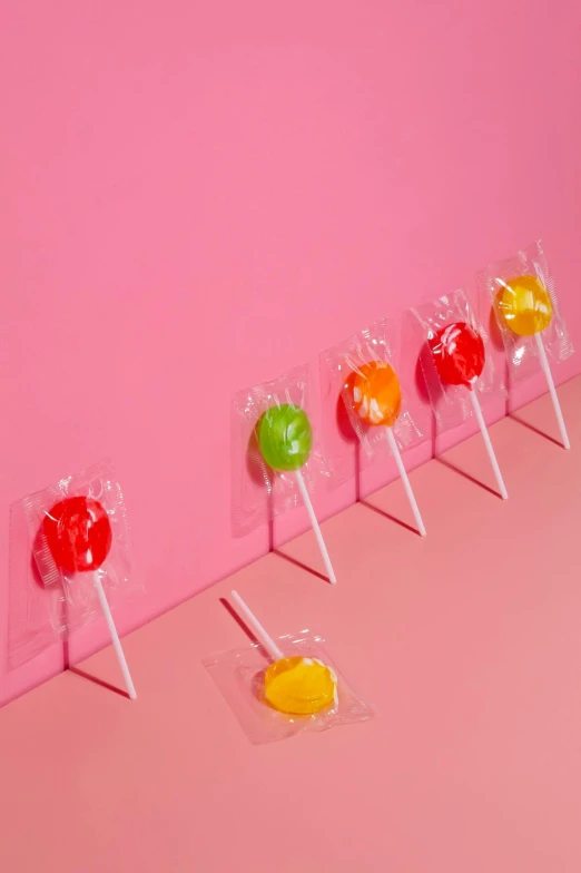 candy pops are lined up on a pink surface