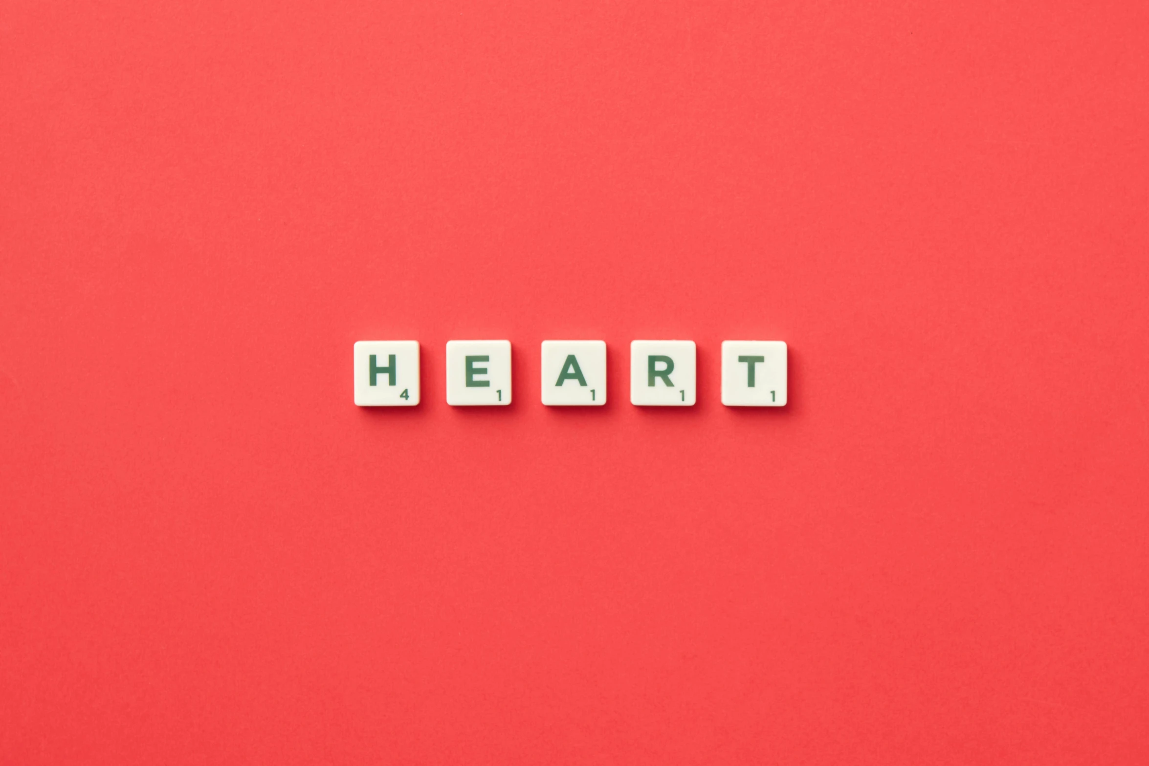 small wooden blocks spelling the word heart on a red background