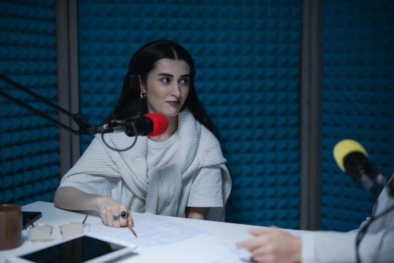 a woman sitting in front of a microphone while speaking into a phone