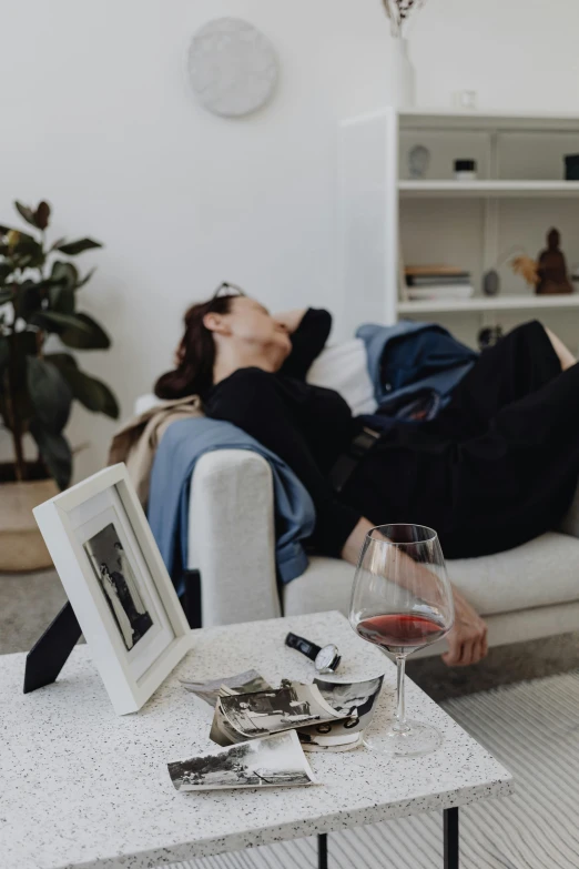 a woman laying on a couch next to a glass of wine