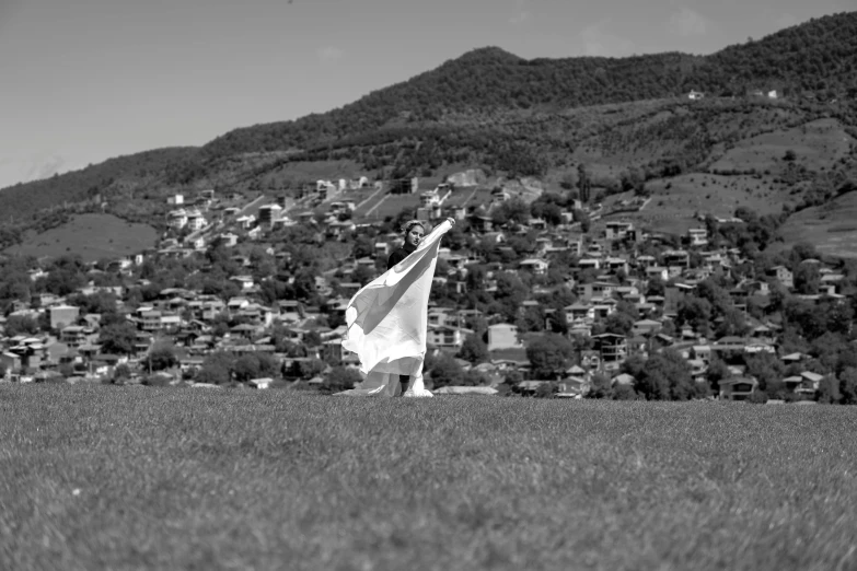 a woman holding up a white kite in the grass