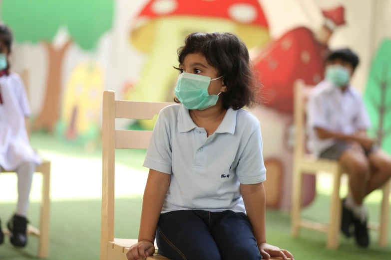 a child with a face mask sitting in a chair