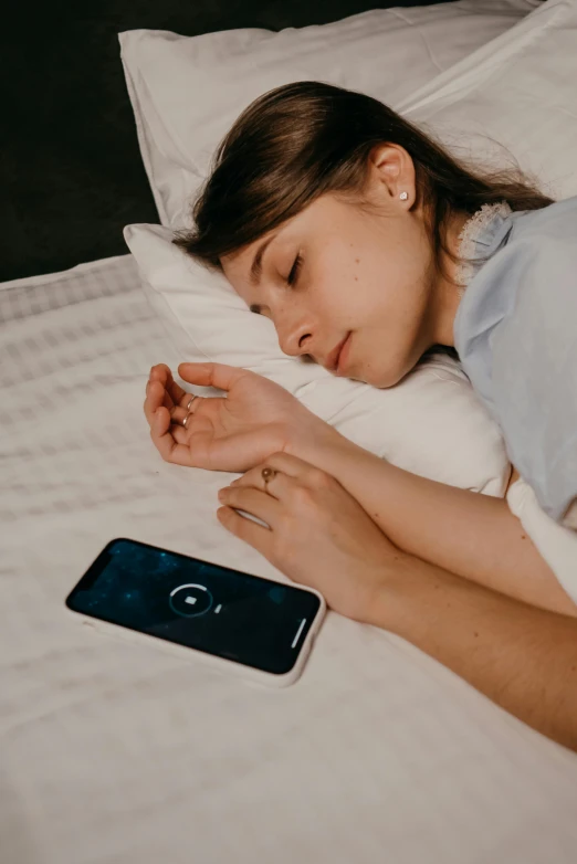 a woman sleeping on a bed next to a phone