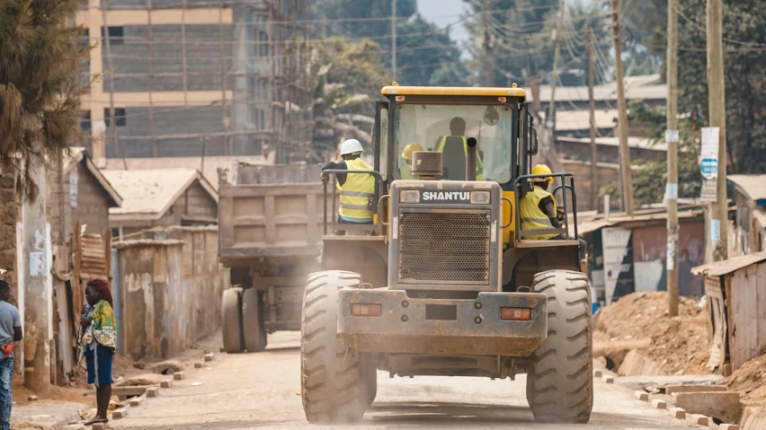 a large tractor on the road with some men standing nearby