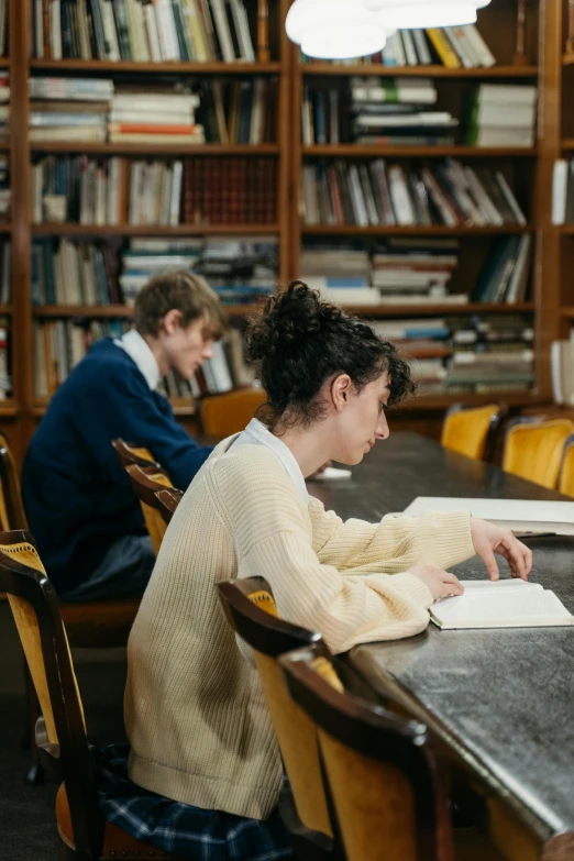 two people sitting in chairs and studying in a liry
