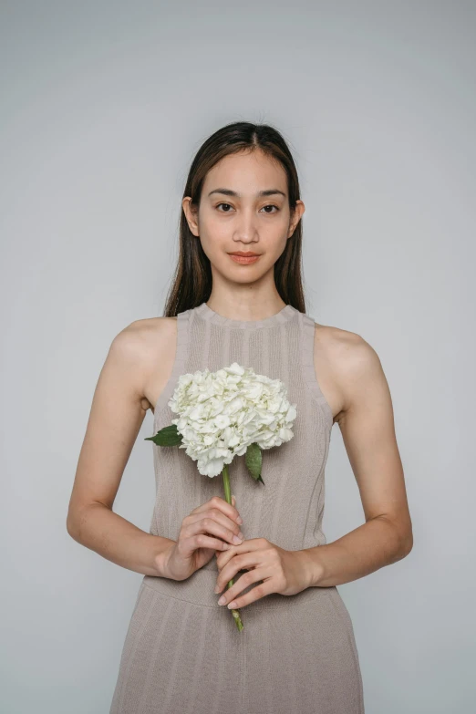 a young woman holds a white flower in her hands