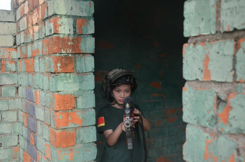 a little boy wearing a helmet with a camera next to brick wall