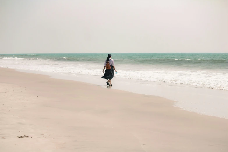 man walking down the beach near the ocean