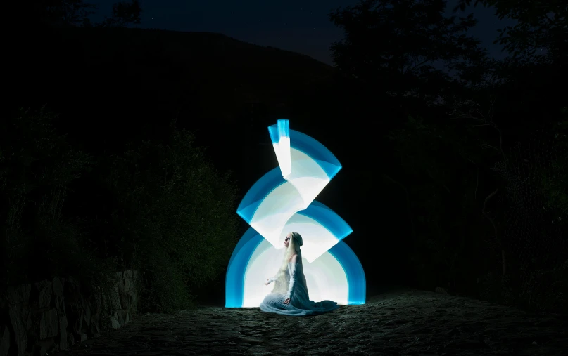 woman in white dress standing against a colorful sculpture