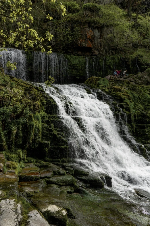 people are sitting at the base of a waterfall