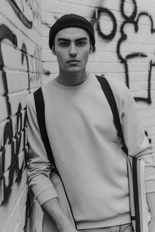 a young man standing next to graffiti on a wall