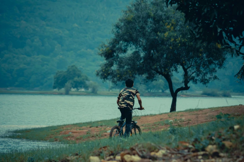 a man riding a bike down a hillside next to a lake