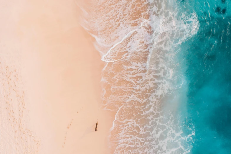 two people stand on a beach with the waves rolling in