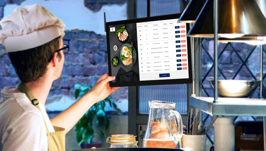 a chef holds up an ipad on top of a counter with some food and utensils