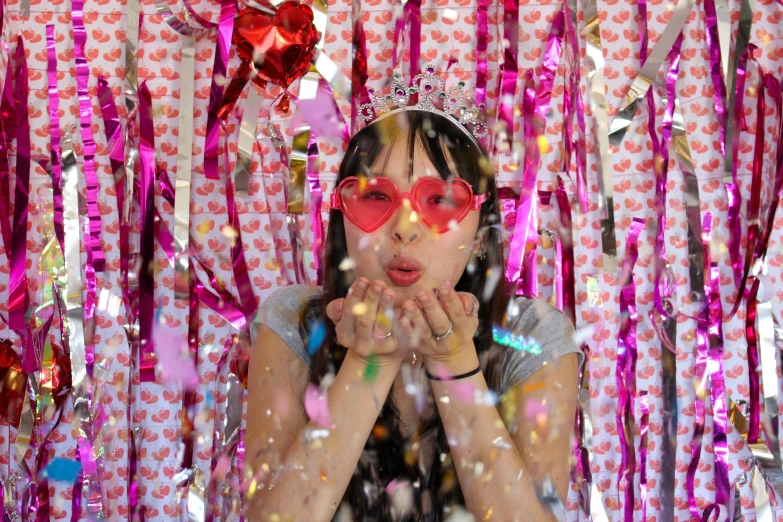 a woman in a crown and red sunglasses with confetti over her eyes