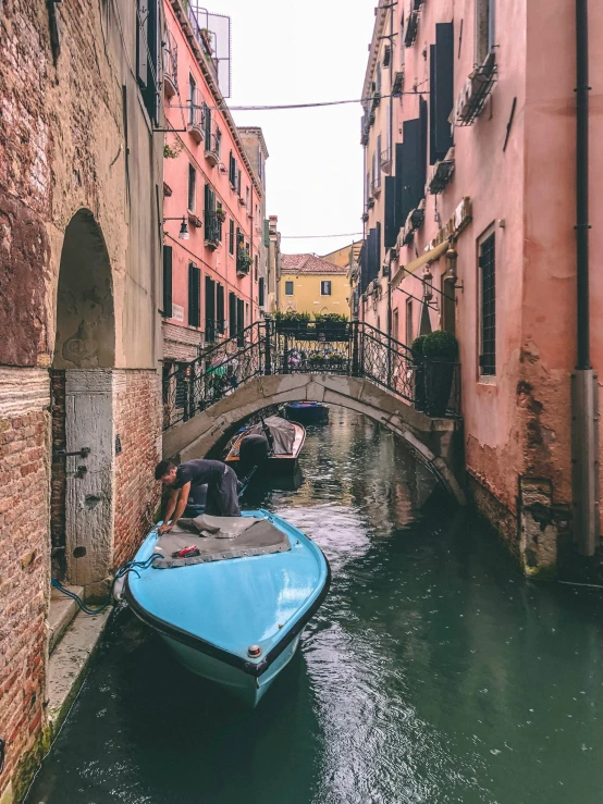 small boats going under an old bridge in venice