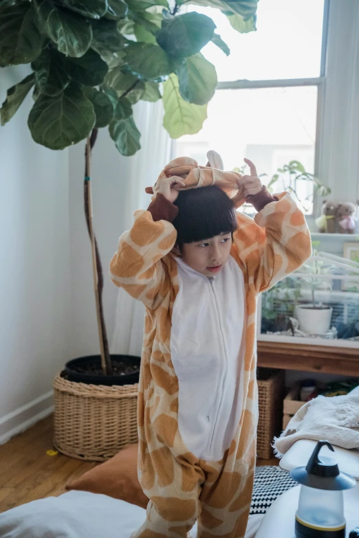 a boy standing wearing giraffe costume and covering his eyes