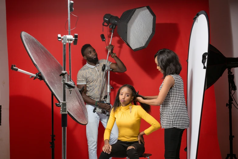 three people standing in a red room with cameras