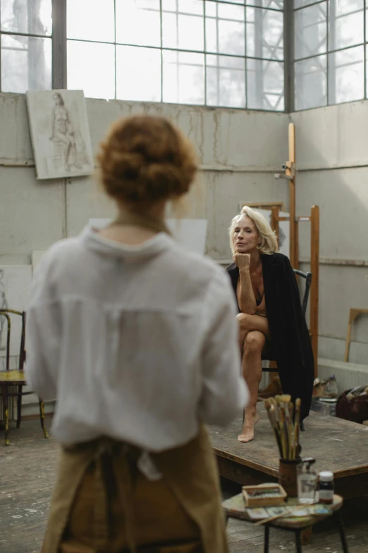 two women sitting in a room with artwork on the walls