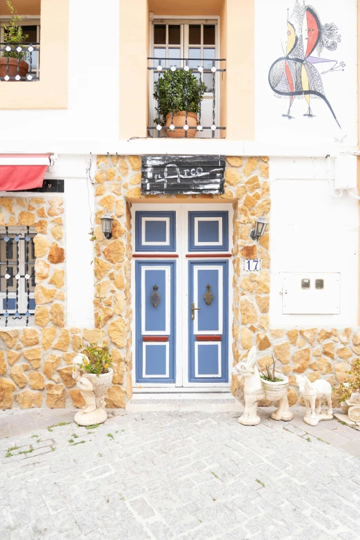 the building with stone walls and a large door has two plants