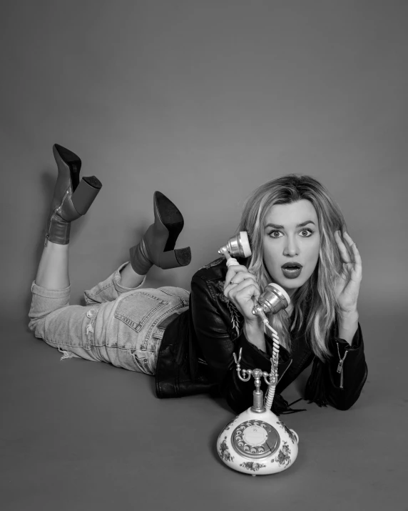 a black and white po of a woman on the floor holding a telephone