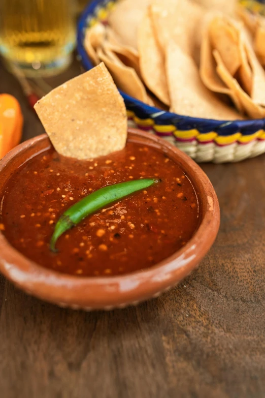 a bowl of food with tortilla chips and a small green chili