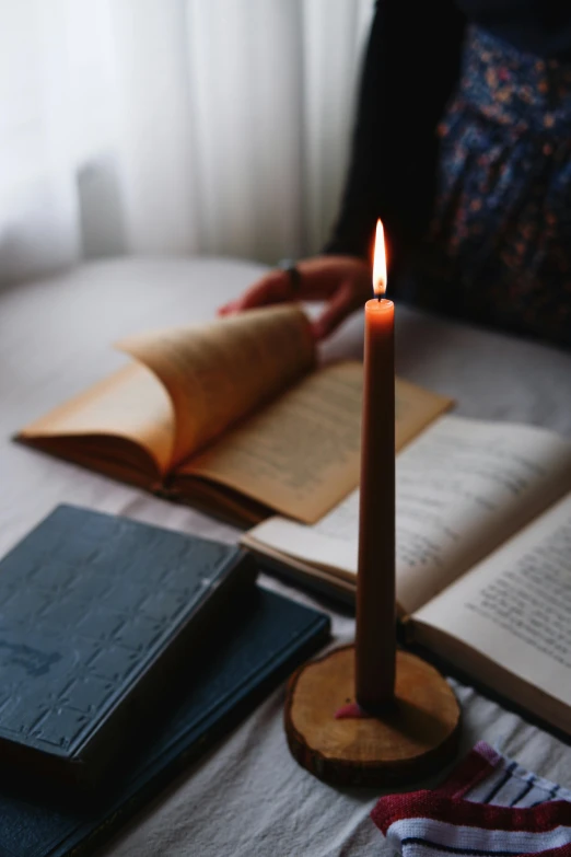 a candle and books sit on a table next to the open book