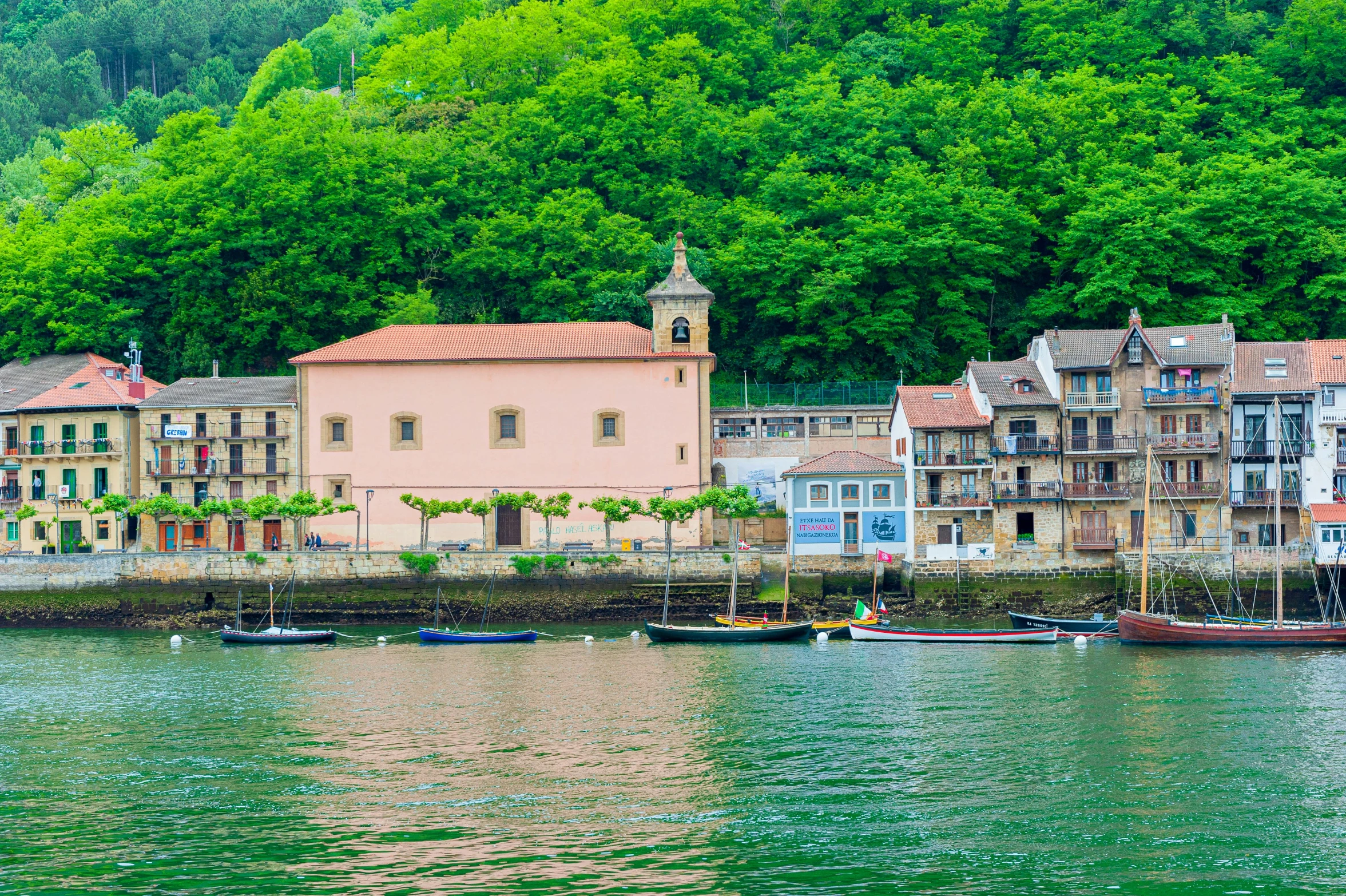 old buildings beside a small waterway near a forest