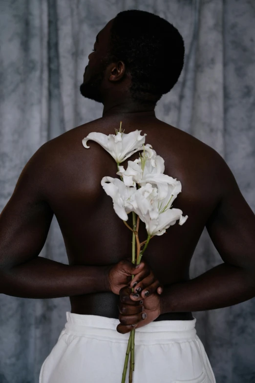 a man holding white flowers in front of his back