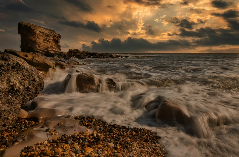 rocks on the beach in front of stormy skies