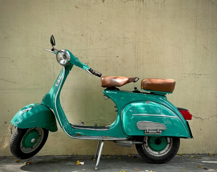 an old scooter is sitting by the wall