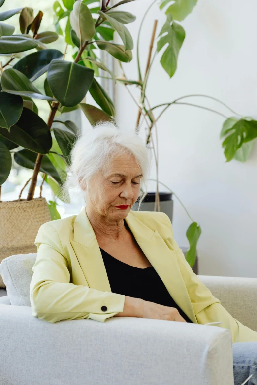 an old lady with white hair sitting on a couch looking down