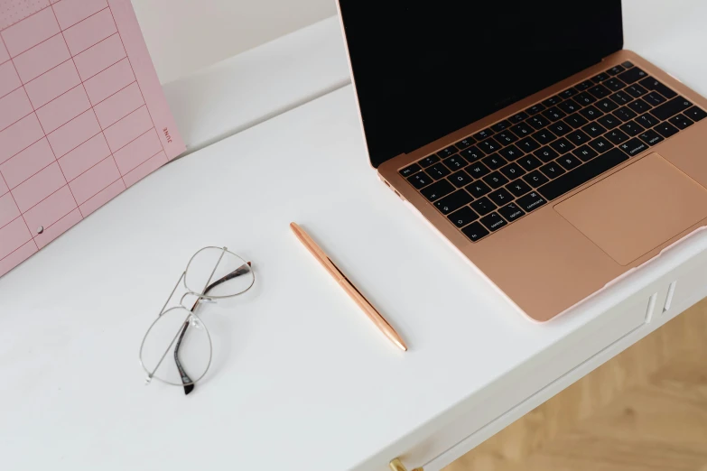 a keyboard and glasses on a desk next to a laptop