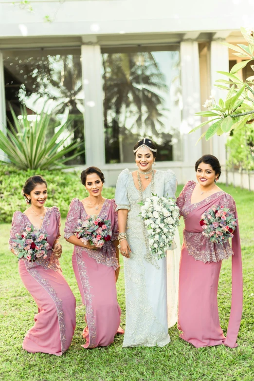 a wedding party poses in front of a house