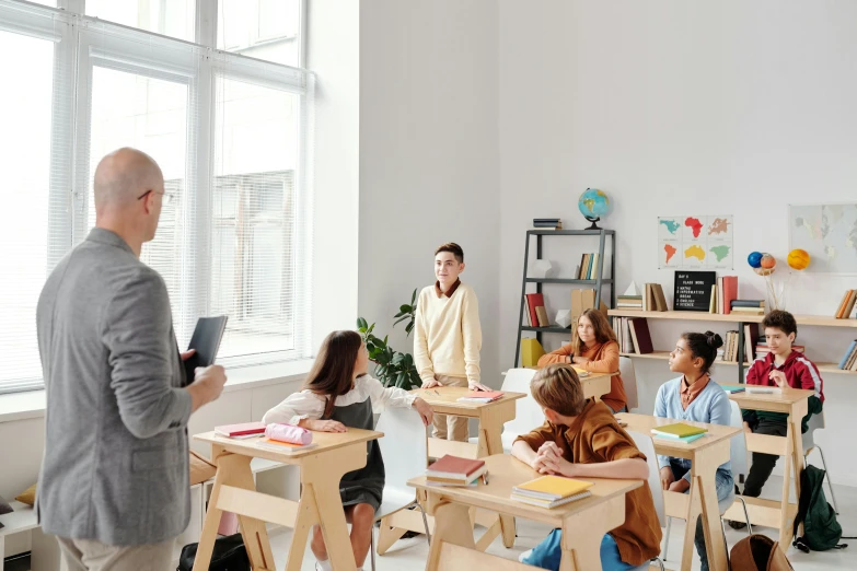 children are in a classroom all sitting and standing