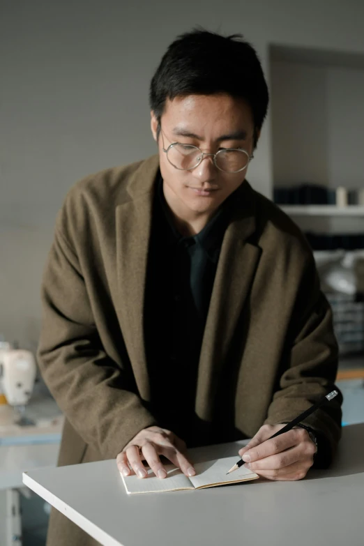 a man in glasses working on some things with paper