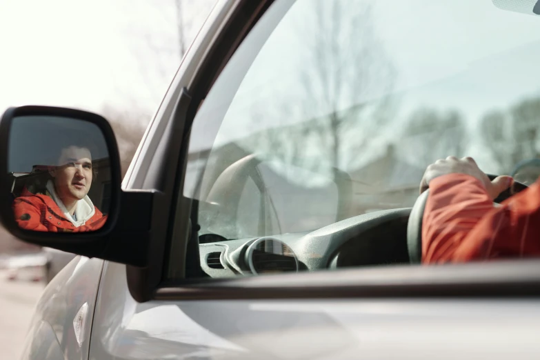 a woman holding her car steering wheel with both hands in the mirror