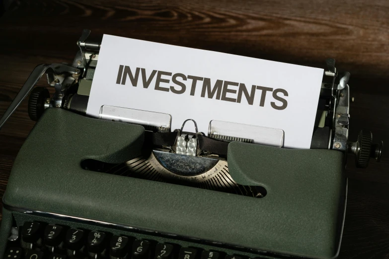 an old - fashioned green typewriter displaying a note with the words investments