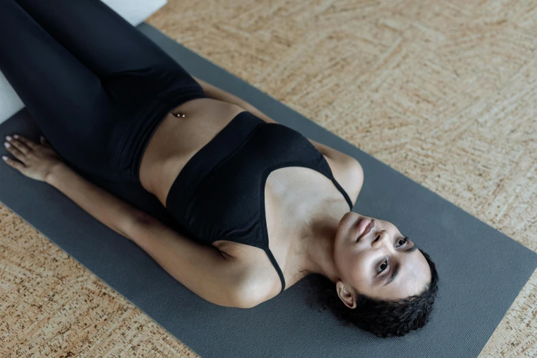 a woman in black outfit laying on a mat