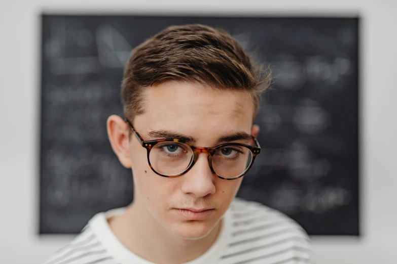 a young man wearing glasses is looking at the camera