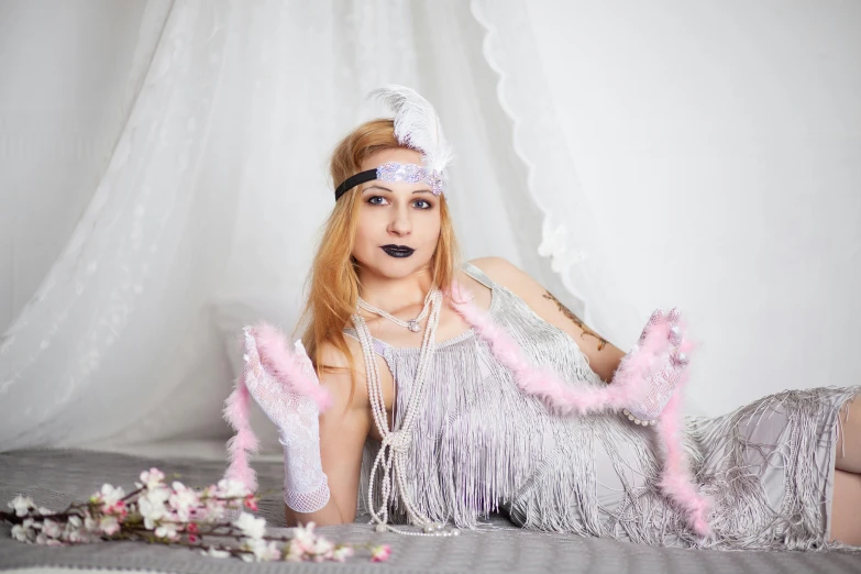 a woman in a silver dress posing on a bed