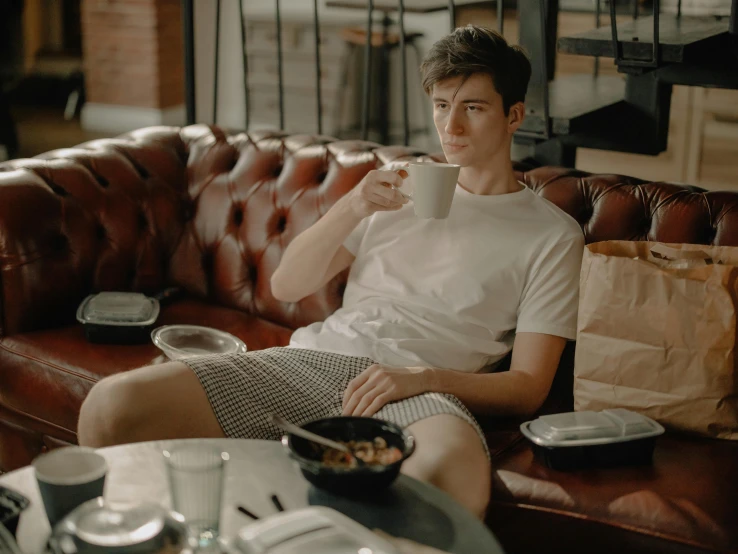 a man is drinking coffee sitting on a couch