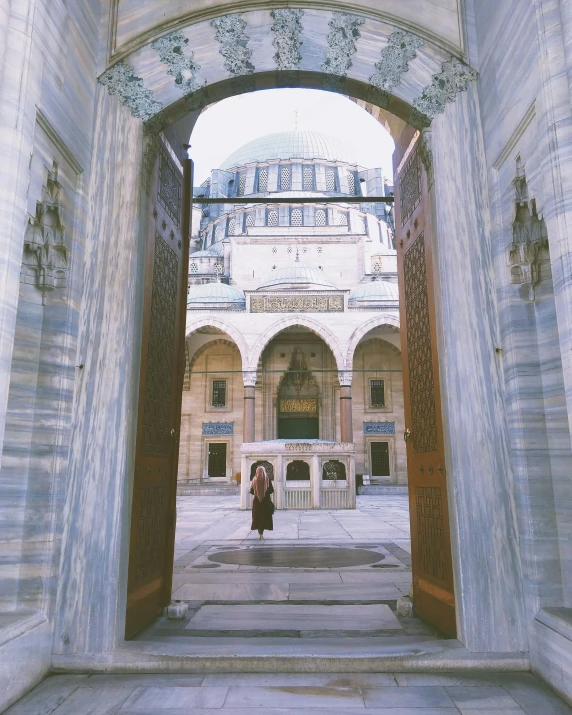 a woman standing outside an archway looking into a building