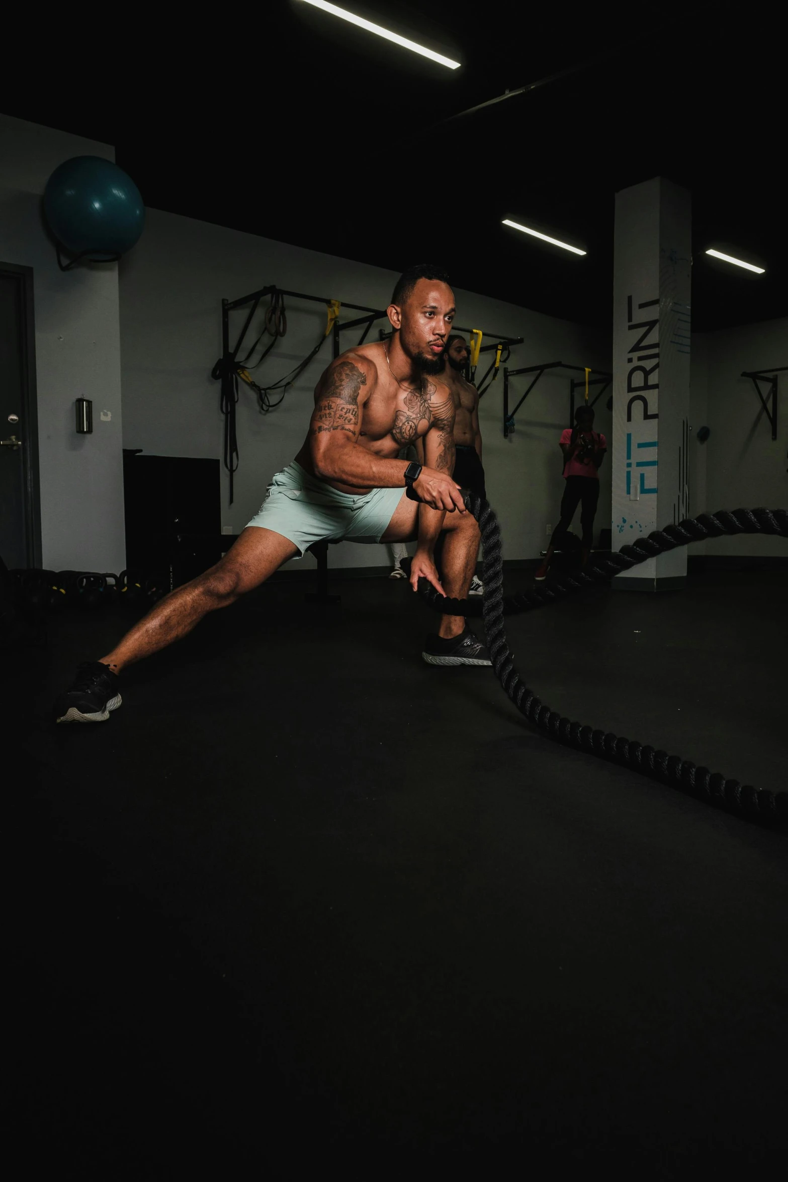 a man in shorts with his arms up lifting a rope