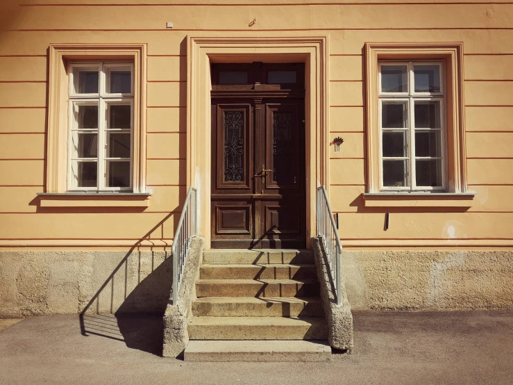 stairs leading to a brown door with two windows