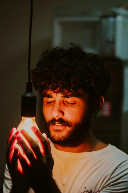 a bearded man is holding a light bulb